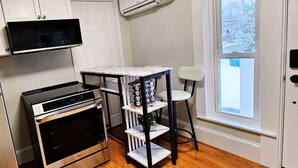 A compact kitchen with a built-in oven, microwave, and a small table with a chair.