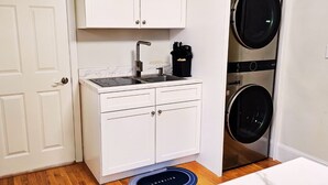 A compact kitchen with a sink, cabinets, and a built-in washer and dryer.