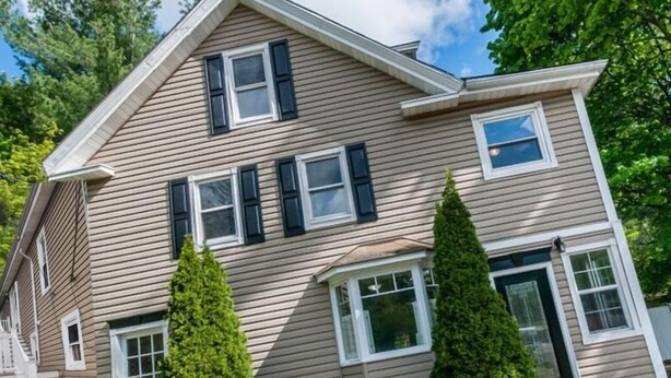 A two-story house with a gabled roof, multiple windows, and a front porch.