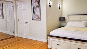 A bedroom with a bed, a nightstand, a lamp, and a wall-mounted light fixture.