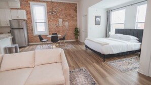 Een modern appartement met keuken, eethoek en een groot bed.