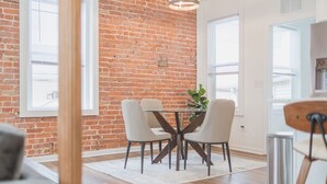Een eetgedeelte met een bakstenen muur, een ronde tafel en vier stoelen.