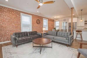 Relax in this stylish living room with a brick accent wall, tufted sofas, and a large window.
