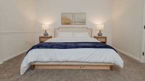Ein Schlafzimmer mit einem Bett, zwei Nachttischen, einem Kopfteil und zwei Wandleuchten.