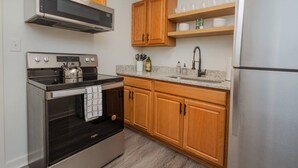 Una cocina moderna con electrodomésticos de acero inoxidable, armarios de madera y una encimera de granito.