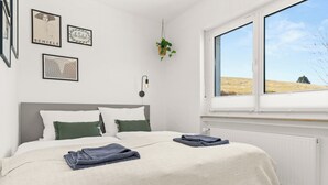 Un dormitori amb un llit, una finestra amb vista a un camp i decoracions murals.