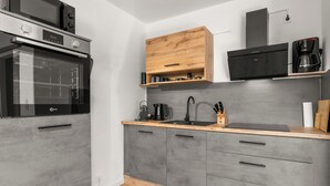 Una cuina moderna amb forn incorporat, cafetera i un armari de fusta sobre la taulella.