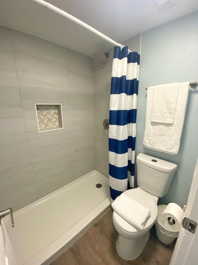 A bathroom with a shower, toilet, and a towel rack.