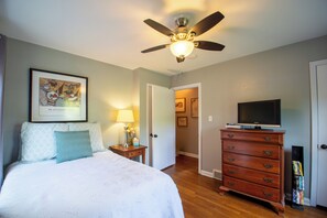 A bedroom with a bed, a dresser, a ceiling fan, and a TV. - 4-bedroom Remodeled St Matthews Cape Cod (Louisville)