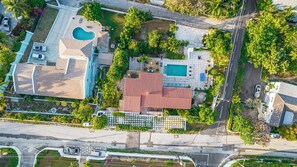Eine Luftaufnahme eines Wohnhauses mit Pool, einer überdachten Terrasse und einem Gebäude mit rotem Dach.