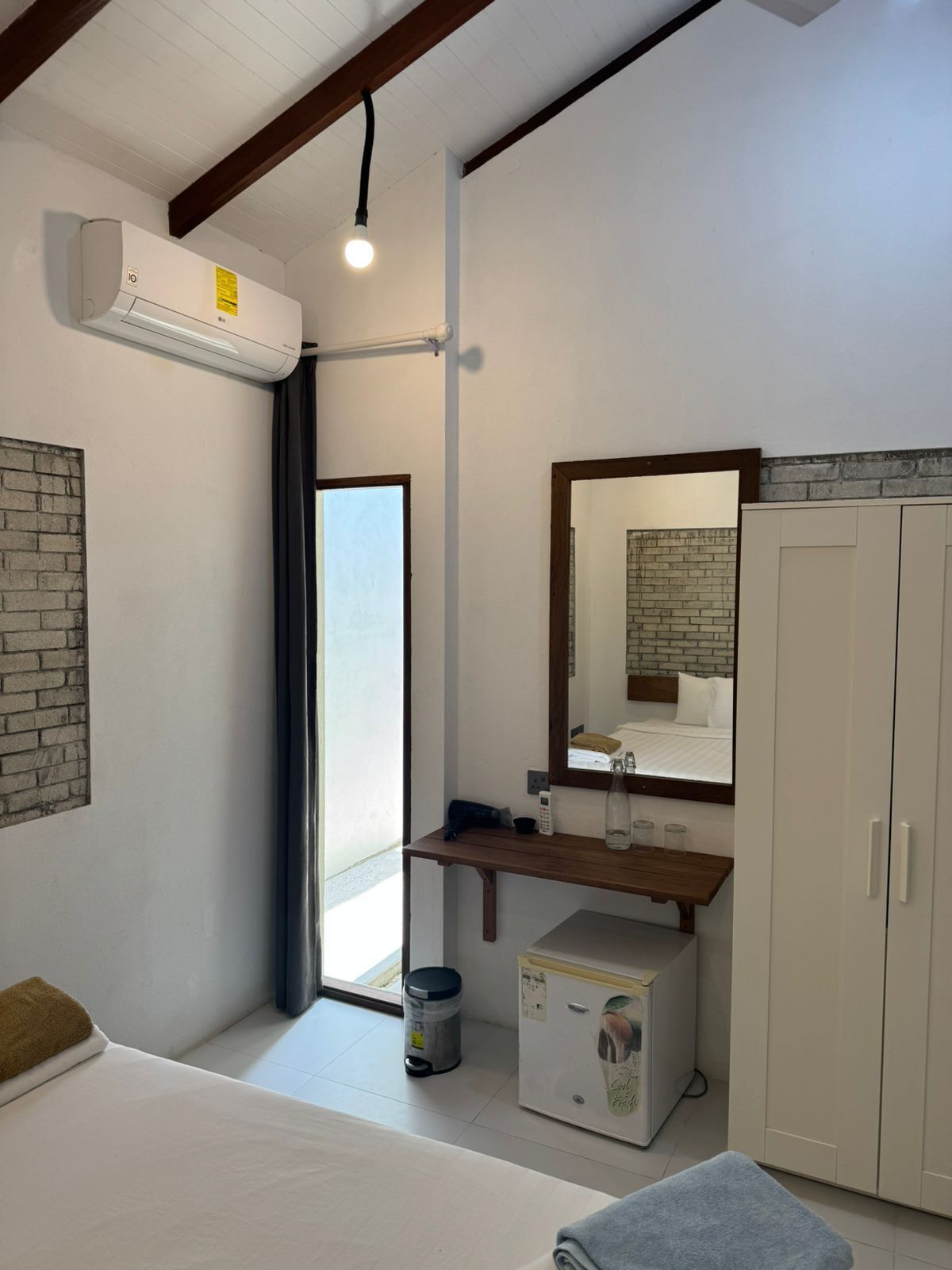 Une chambre à coucher comprenant un lit, une table de chevet, un miroir, une armoire et un appareil de climatisation.