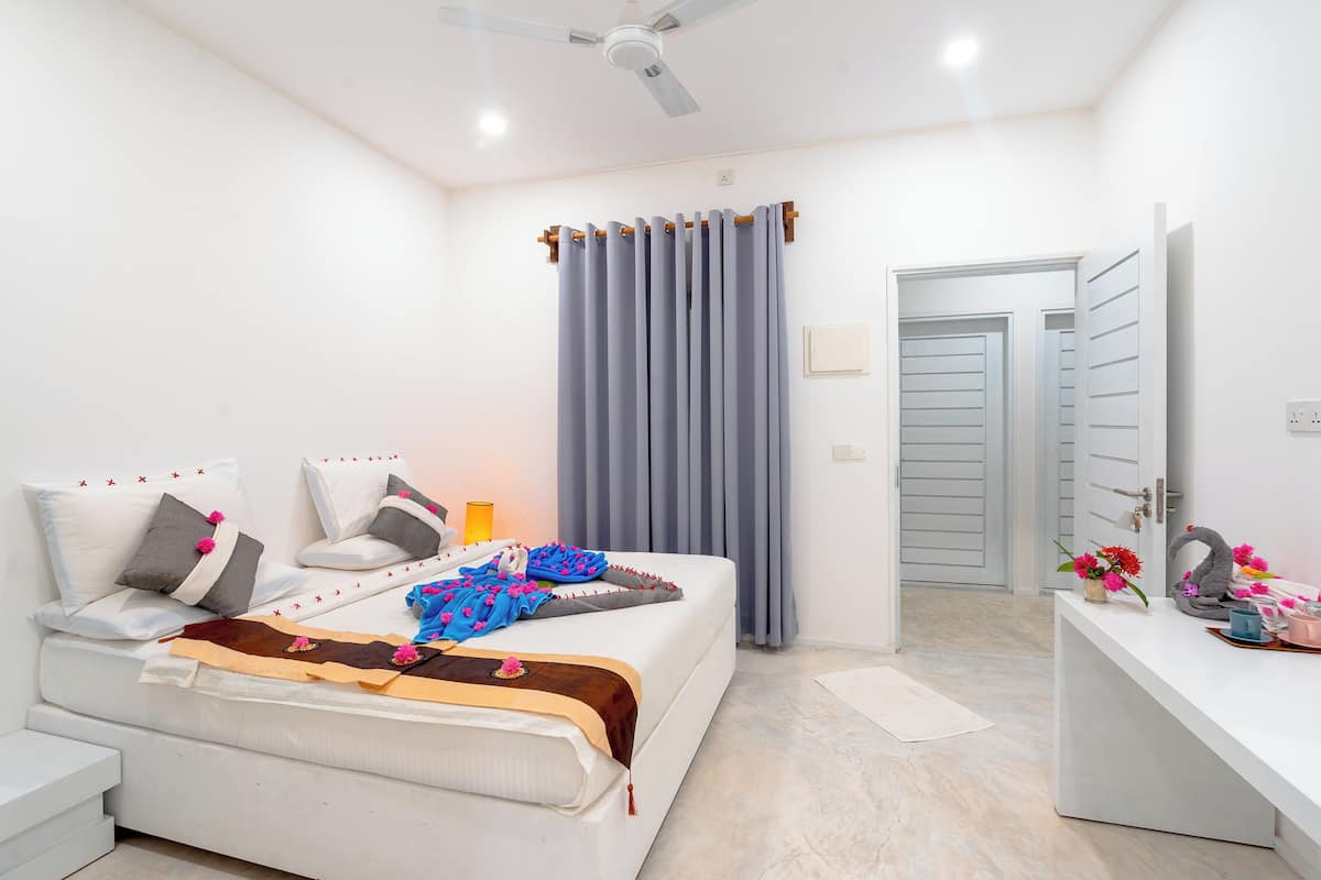 A modern bedroom with a bed, bedside table, and a desk with a mirror.