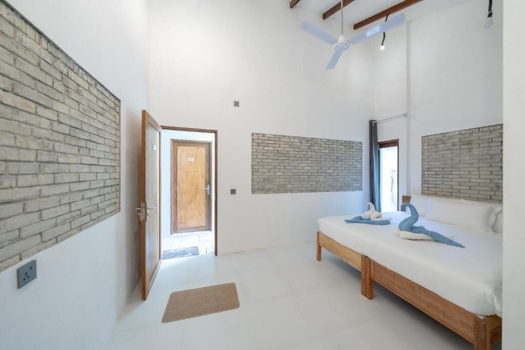 Un dormitorio con cama, un banco de madera y una pared de ladrillo decorativa.