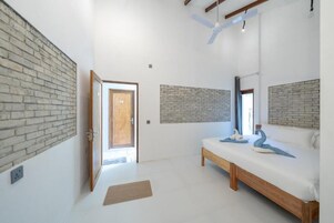 Quarto com uma cama, um banco de madeira e uma parede de tijolos decorativa.