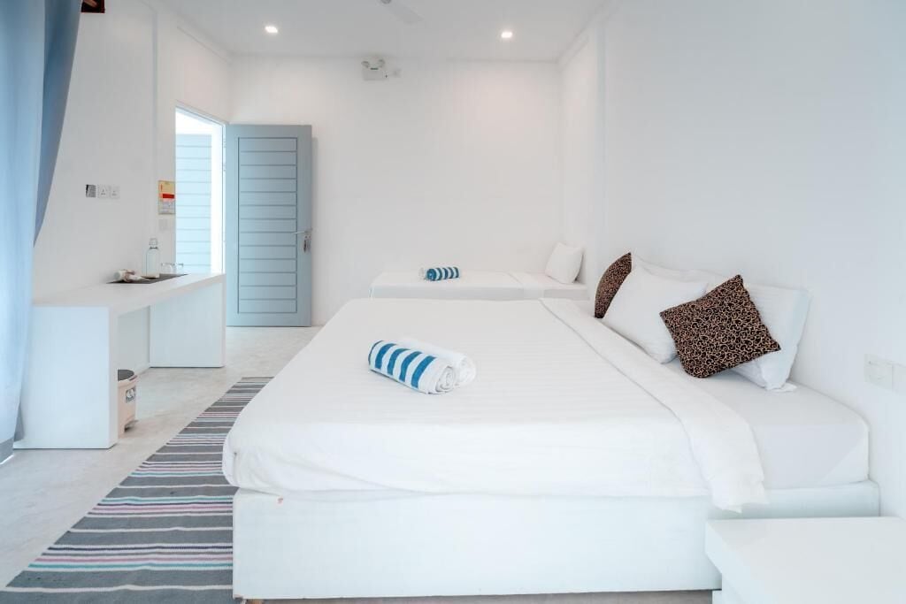 A hotel room with a large bed, a small sofa, a desk, and a window.