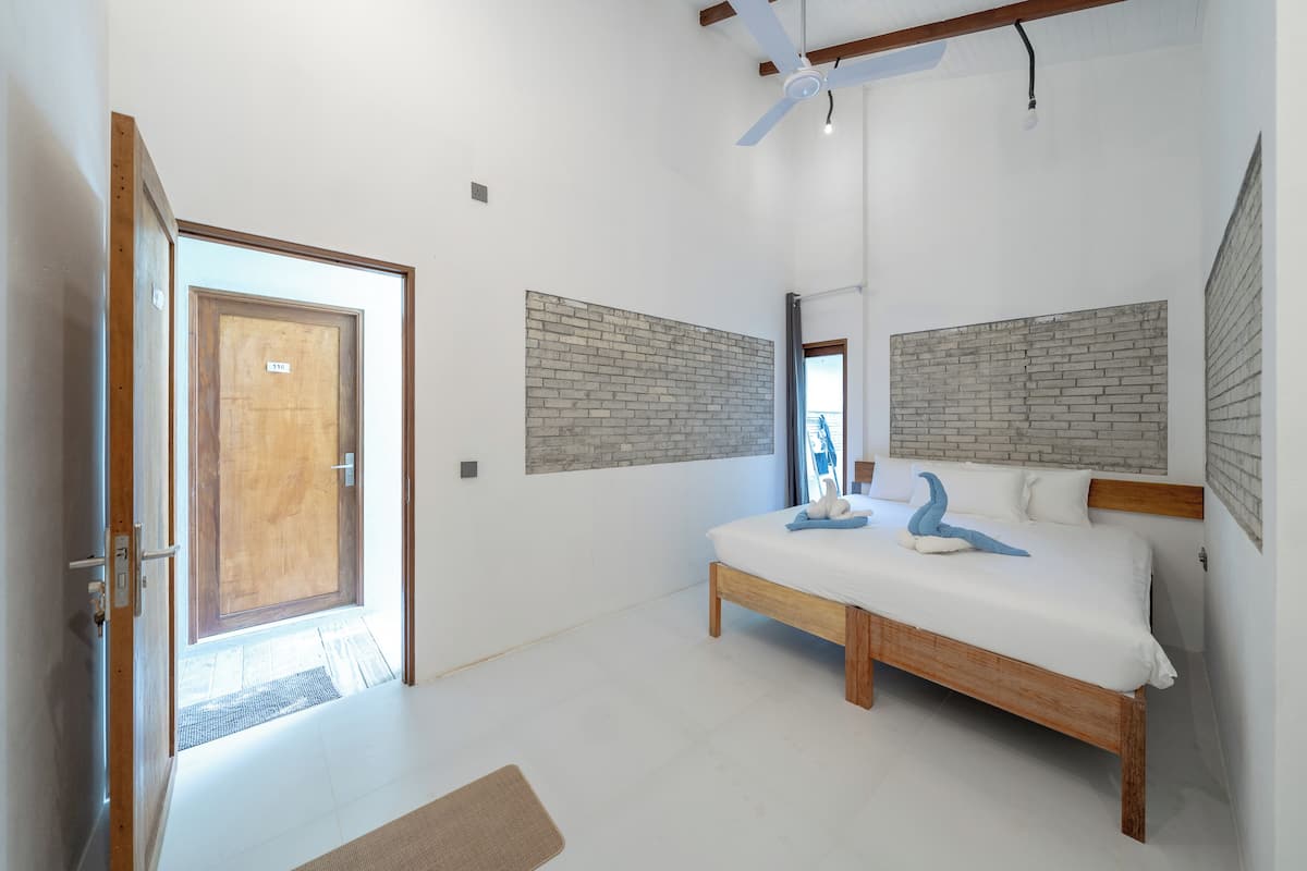 A bedroom with a wooden bed, a brick-patterned headboard, and a door leading to the outside.