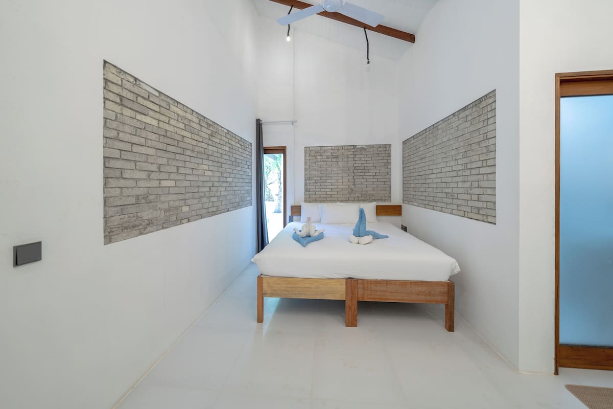 A bedroom with a wooden bed, white walls, and brick-patterned headboards.