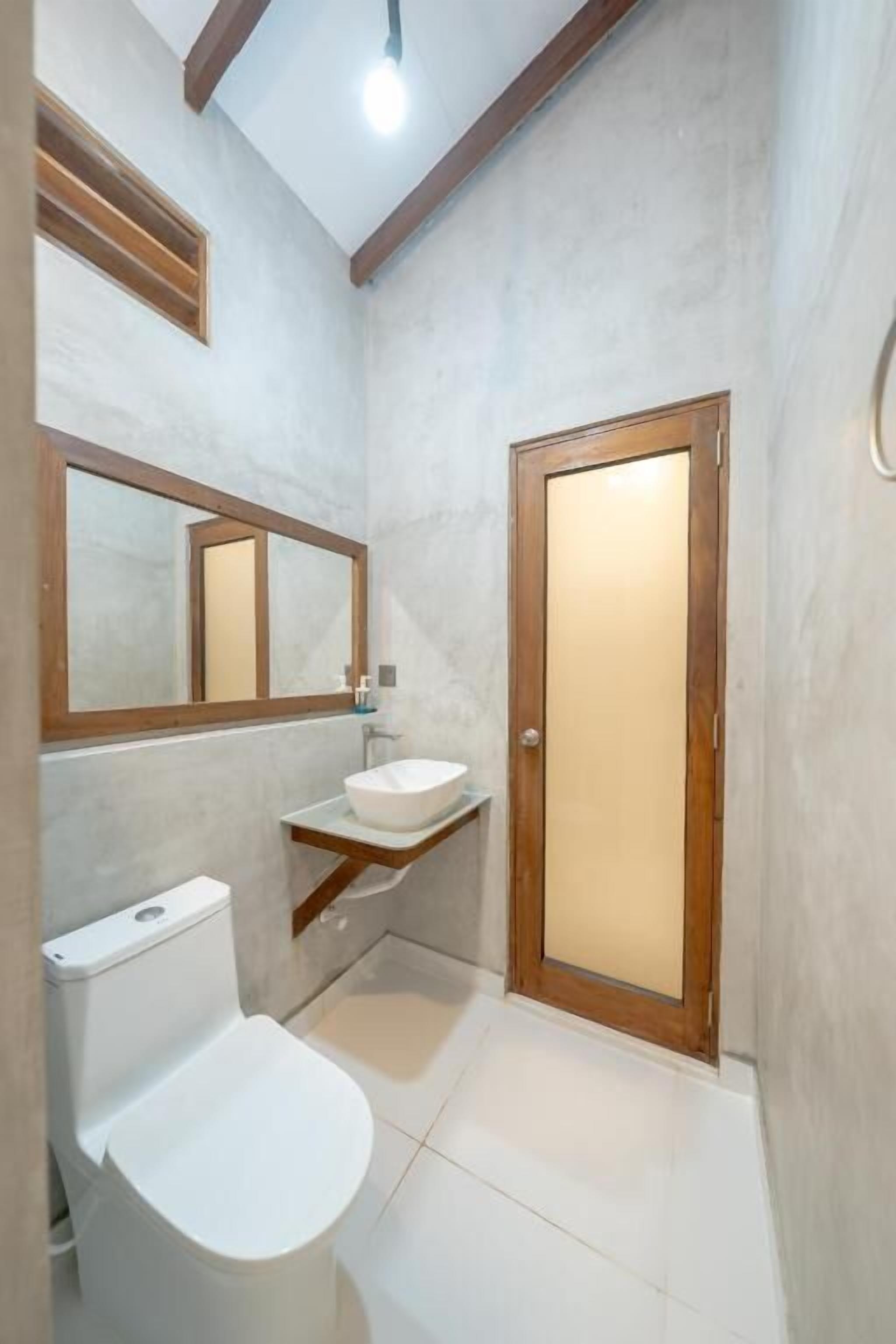 A small bathroom with a toilet, a sink, and a mirror.