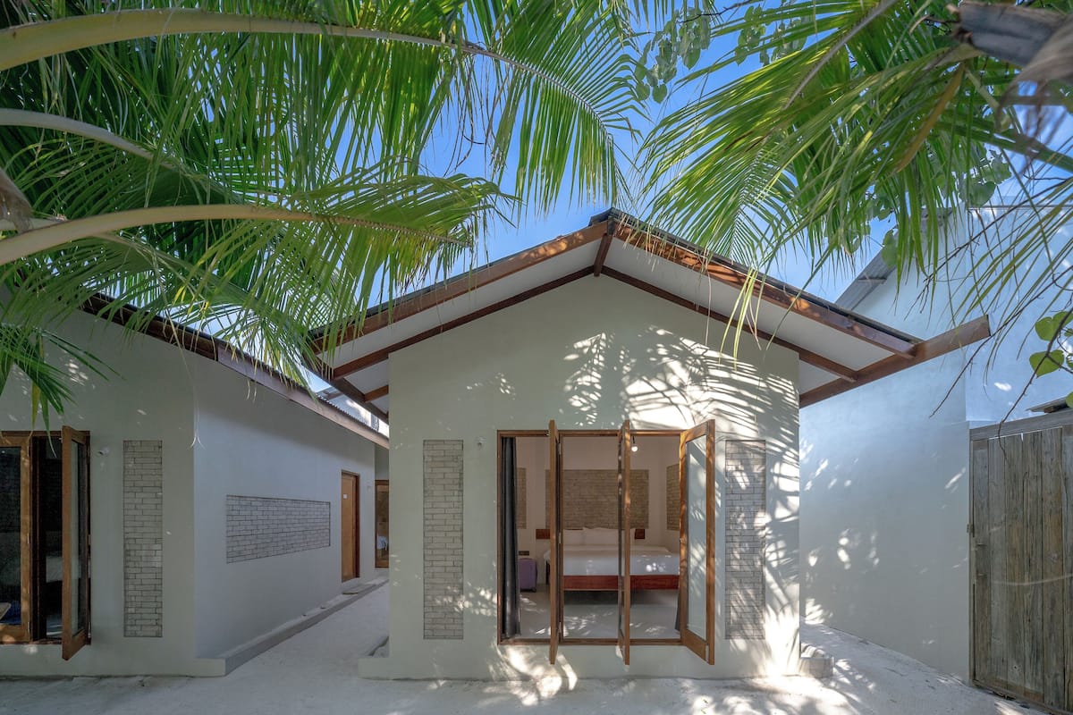 A modern, single-story building with a large sliding glass door leading to a bedroom.