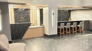 Un espace d’accueil moderne doté d’un sol en marbre, d’un comptoir de réception et d’un bar avec des tabourets.
