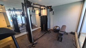 Une salle de sport équipée de matériel d’exercice, d’un banc et d’une chaise.