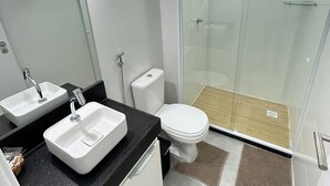 Une salle de bain moderne avec deux lavabos, des toilettes et une douche à parois de verre.