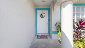 A white building with a turquoise door and a small porch area. - 5 Star, 3 bd Home, Heated Pool Located D-town Cape (Cape Coral)