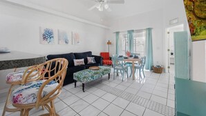 A modern living room with a sofa, chairs, a dining table, and artwork on the walls. - 5 Star, 3 bd Home, Heated Pool Located D-town Cape (Cape Coral)