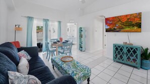 A spacious living area with a sofa, a dining table, and a ceiling fan. - 5 Star, 3 bd Home, Heated Pool Located D-town Cape (Cape Coral)