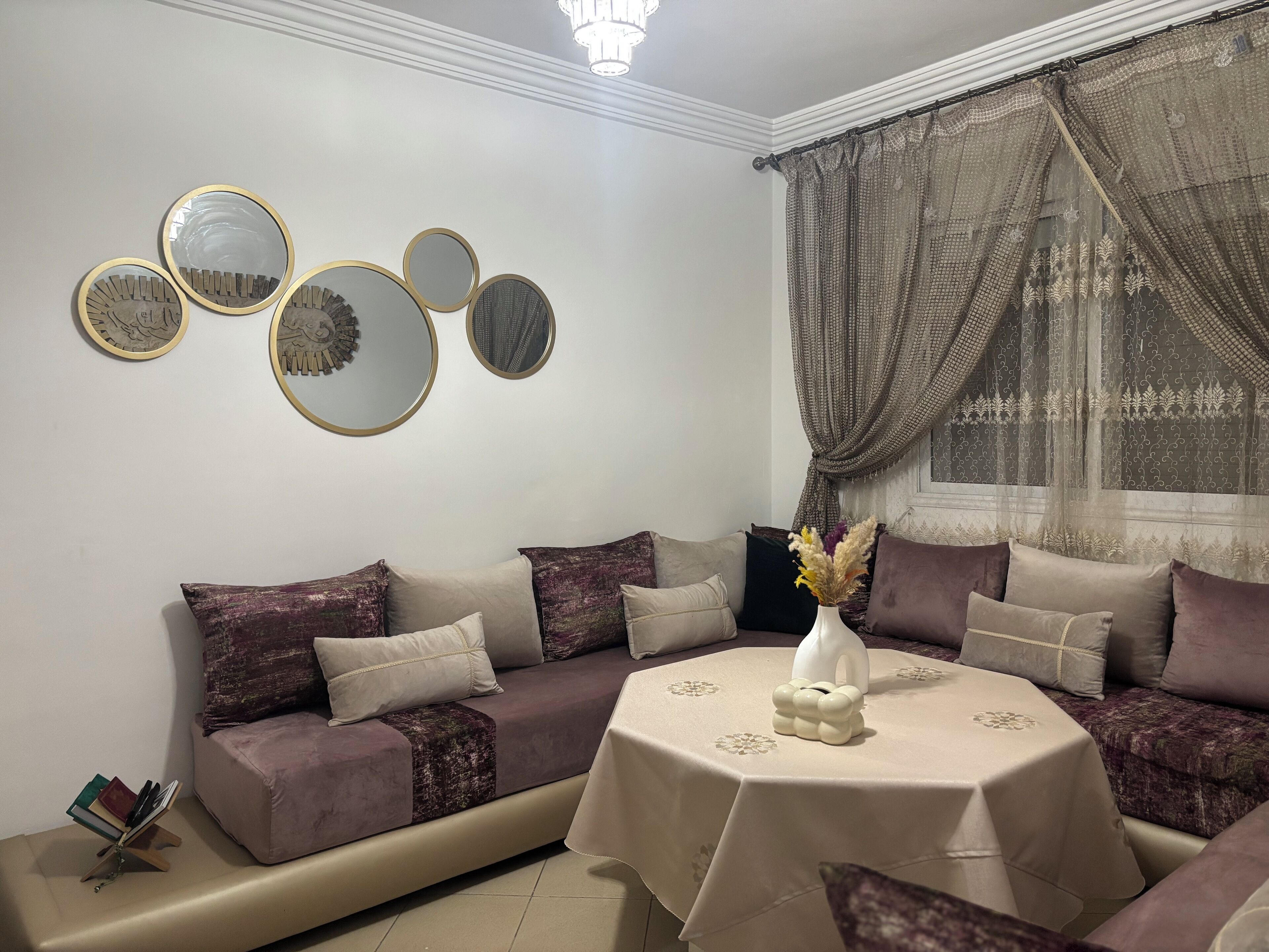 A living room with a sofa, a small table with a vase, and wall-mounted mirrors.