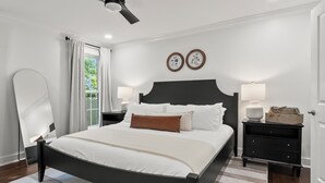 Un dormitorio con cama, mesitas de noche, ventilador de techo y ventana con cortinas.
