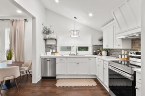 A modern kitchen with white cabinetry, a stainless steel dishwasher, and a built-in oven.