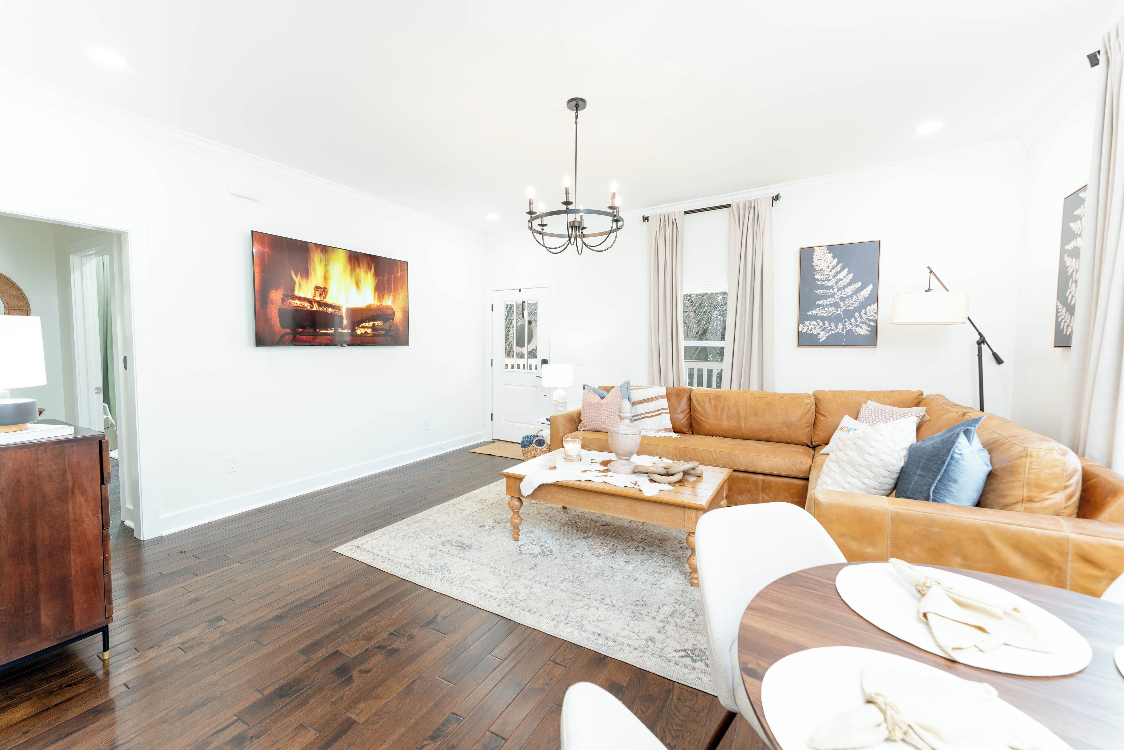 A living room with a brown leather sofa, a wooden coffee table, and a dining table with plates.