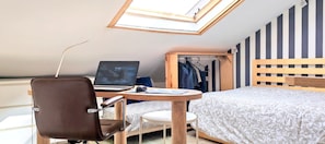 Une chambre comprenant un lit, un bureau avec un ordinateur portable, une chaise, une petite table et une armoire.
