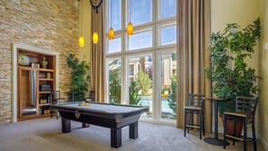 A pool table in a room with a brick wall, large windows, and a view of a swimming pool. - New Luxurious 1BR Apartment Heated Pool Spa Sauna (Reno)