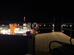 Een buitengebied met een houten terras, een bar en een zithoek.