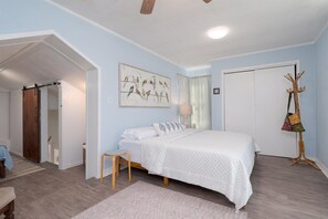 A bedroom with a bed, a chair, a coat rack, and a door.