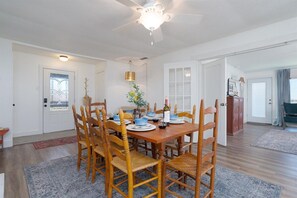 A dining area with a wooden table set for six, surrounded by six wooden chairs.