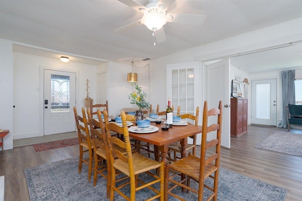 A dining area with a wooden table set for six, surrounded by six wooden chairs.