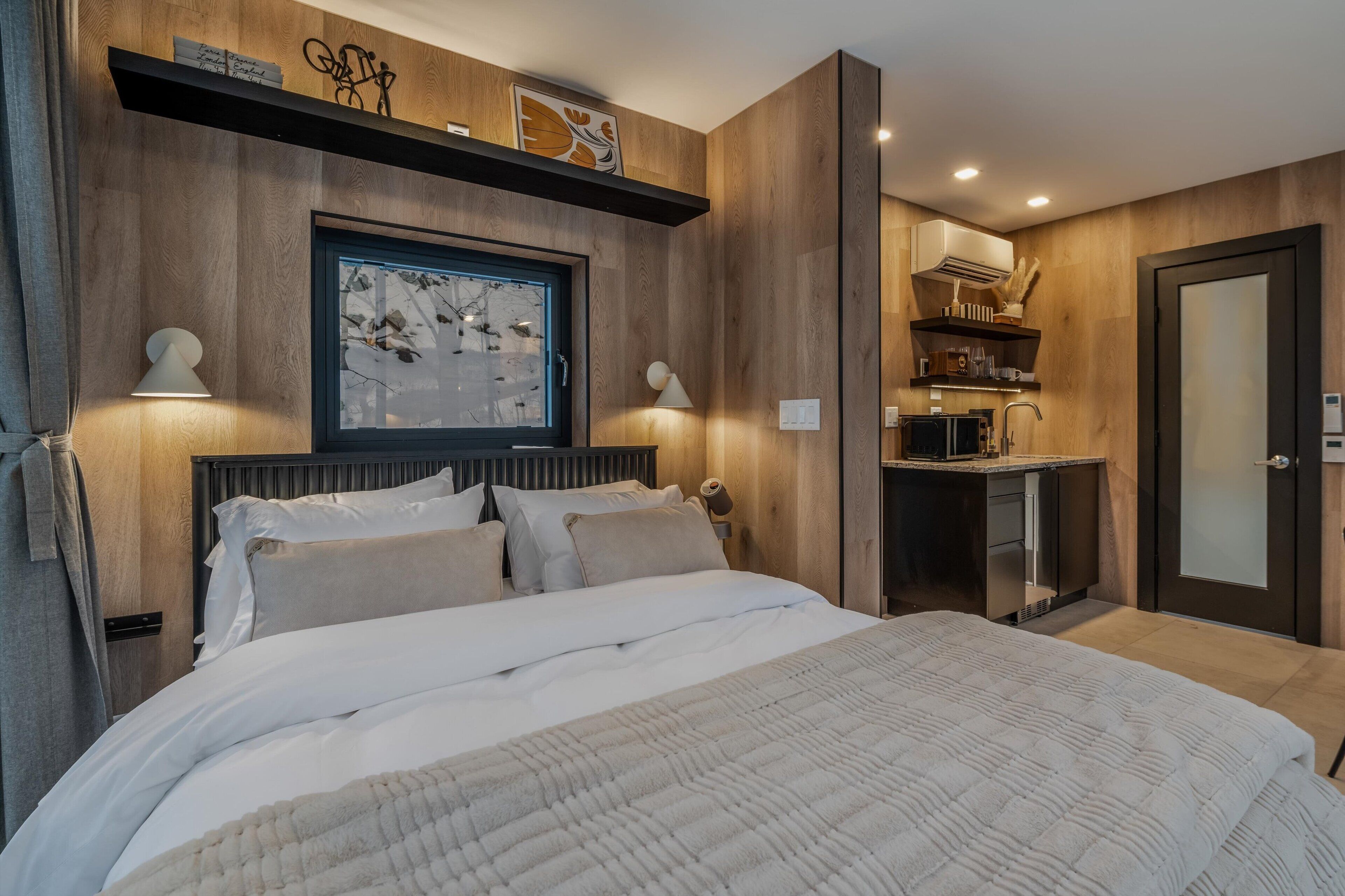 A bedroom with a large bed, a nightstand, a desk, and a wardrobe.