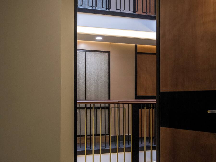 A hotel room with a bed, a wooden partition, and a view of a balcony with a railing.