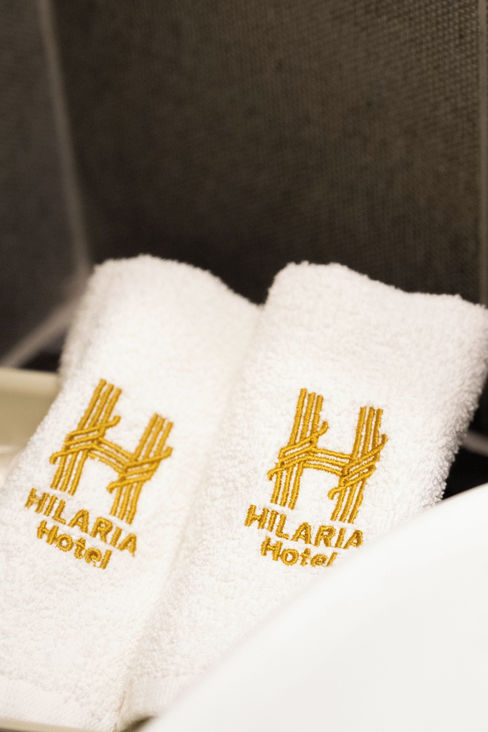 Two white towels with embroidered text and a logo, placed on a surface.
