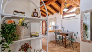 A rustic dining area with a wooden table and chairs, surrounded by shelves with books and decorative items. - Air-conditioned apartment a few meters from the sea of ​​about 40 square meters characterized by simple and functional furnishings, located on the first floor and composed of a living room with kitchenette and sofa bed, a bedroom with double bed, bat (Golfo Aranci)
