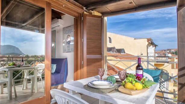 A balcony with a table set for dining, a bottle of wine, and a view of the cityscape. - Air-conditioned apartment a few meters from the sea of ​​about 40 square meters characterized by simple and functional furnishings, located on the first floor and composed of a living room with kitchenette and sofa bed, a bedroom with double bed, bat (Golfo Aranci)