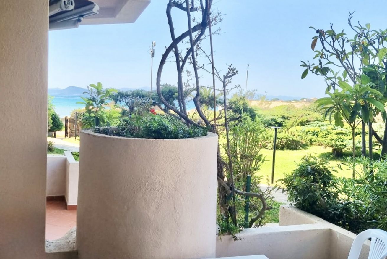 Un balcón con vistas a un jardín ajardinado y al mar.