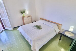 Une chambre à coucher avec un lit, une table de chevet, une commode et une petite plante en pot.