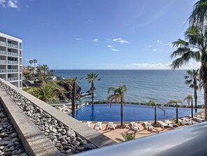 Un resort con piscina, palme e vista sull'oceano.