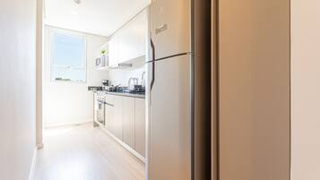Una cocina moderna con electrodomésticos de acero inoxidable, armarios blancos y un amplio ventanal que proporciona luz natural.