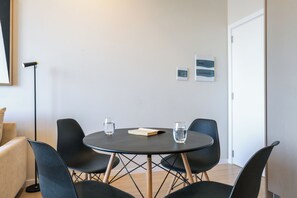 A modern room with a round table, four chairs, two framed pictures on the wall, and a door. - Sky Stays at Life Mariscal (Asunción)