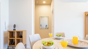 A dining area with a round table, chairs, a bowl of salad, two glasses of orange juice, and a pitcher of orange juice on a tray. - Sky Stays at Life Mariscal (Asunción)